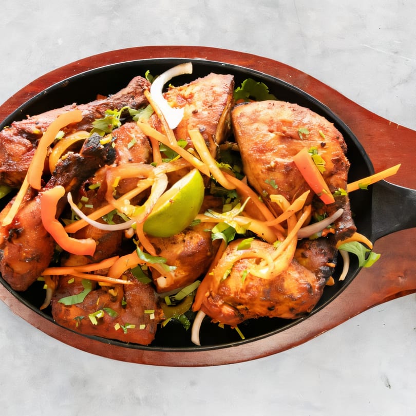 Saffron Indian Cuisine's chicken tikka, garnished with onions, peppers, and a lime wedge.